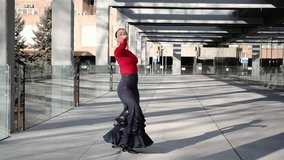 Young woman dancing flamenco in a modern urban setting, wearing traditional attire with red top and floral skirt - Powered by Shutterstock - Get 15% off with code: PIKWIZARD15