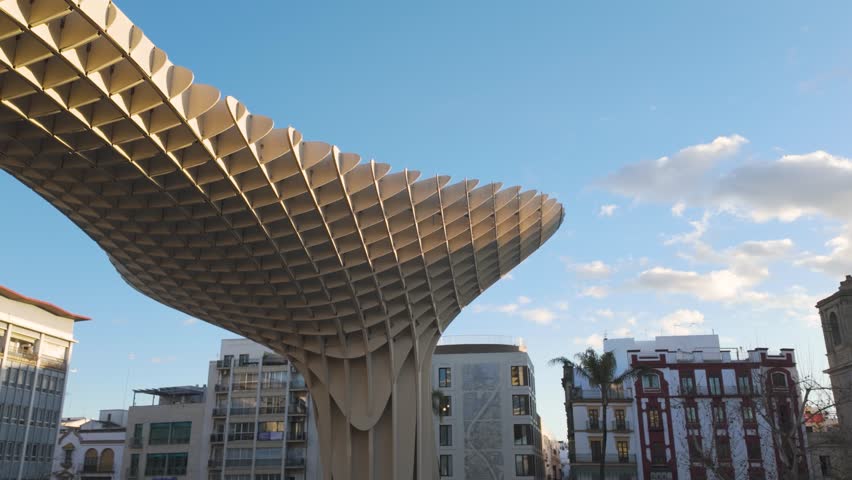 Establishing pan across Setas de Sevilla and Iglesia de la Anunciacion in Seville, Spain, modern and historic contrast