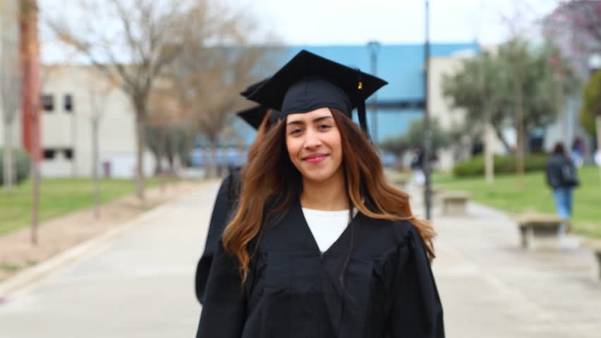Multiethnic graduates wearing gowns and mortarboards, holding diplomas, celebrating their academic achievement on campus