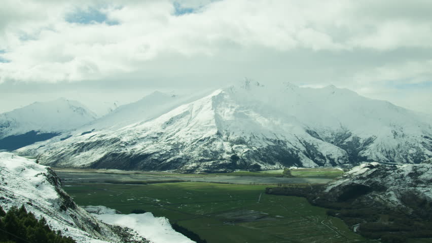 Green field surrounded by snow mountains in Queenstown New Zealand Time Lapse.