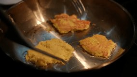A woman flips the latkes frying in a skillet with oil, preparing traditional potato pancakes in vegetable oil. The latkes have a beautifully browned golden crust. - Powered by Shutterstock - Get 15% off with code: PIKWIZARD15