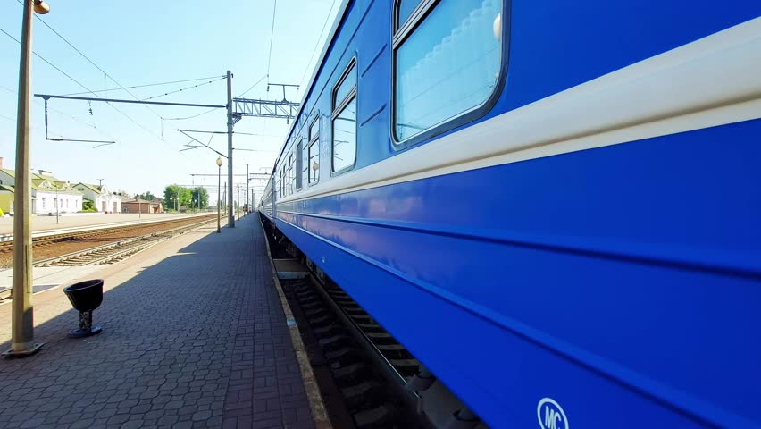 Departure of a blue passenger train from a railway station platform in summer. Concept of passenger transportation by train. Copy space for text