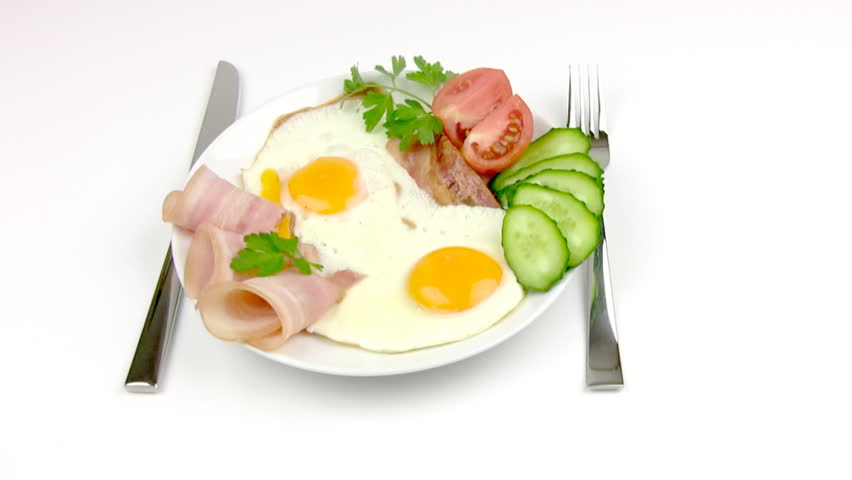On the white plate is: delicious fried eggs, delicate slices of ham, slices of