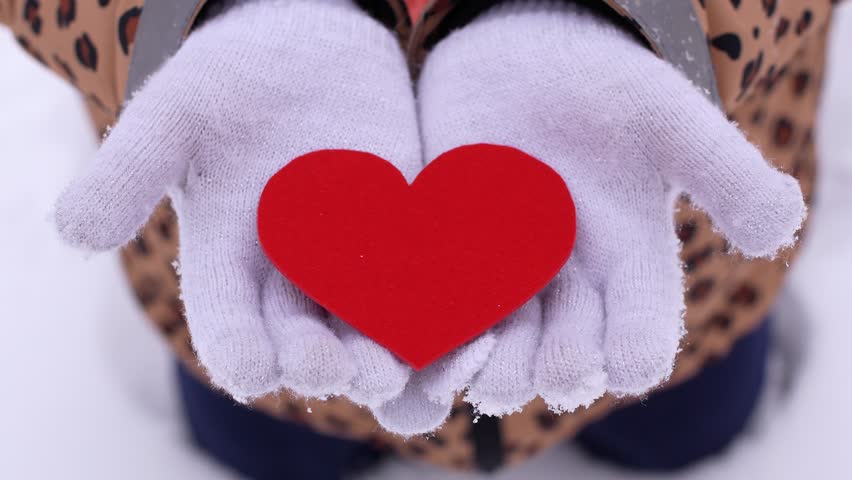 Hands in White Winter Gloves Holding a Red Heart in the Snow