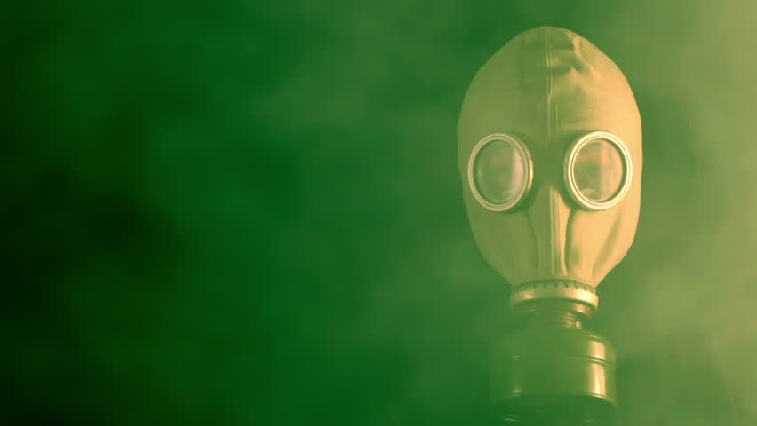 Poison green smoke on a black background. The man raises his head in a gas mask.