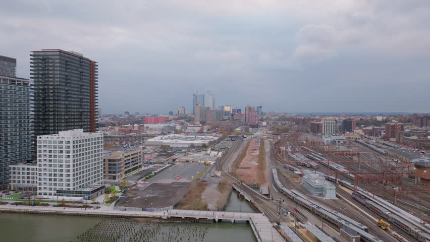 Urban landscape capturing Hoboken and Jersey City soaring skyline with sweeping view of complex railway infrastructure spanning New Jersey aerial panorama