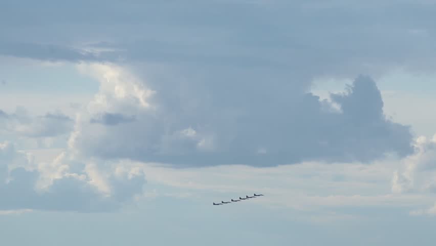 Formation of four airplanes flying through cloudy sky