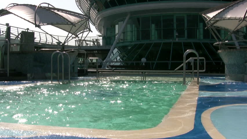 Outdoor swimming pool of large cruise ship during pitching. A bright sunny day.