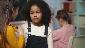 Two multiethnic female friends whispering about their classmate behind her back - Powered by Shutterstock - Get 15% off with code: PIKWIZARD15