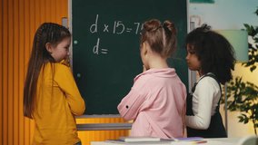 Three multiethnic classmates solving a math equation near the chalkboard, team - Powered by Shutterstock - Get 15% off with code: PIKWIZARD15