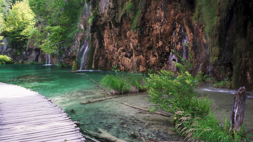 Boardwalk in Plitvice Lakes National Park, Croatia. Transparent Turquoise Colored Waters of the Lake Are Having Ripples. Many Small Waterfalls Flowing Into the Lake. Stedicam Shot