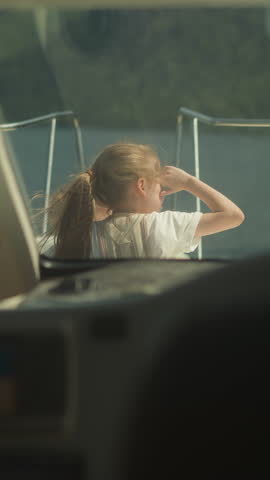 Little girl and junior brother sit on sailboat bow deck view from skipper cockpit. Cute children observe seascape sailing yacht on summer vacation