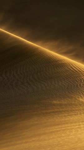 Sandstorm in the deset. Wind blows sand off the dune and carries it away. Sand waving in the wind in dunes in desert. Vertical slow motion shot