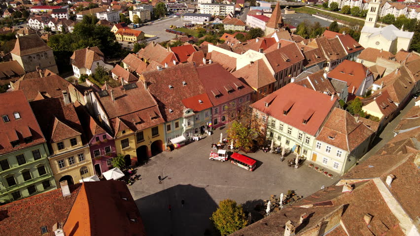 Aerial Shot Of People Walking Amidst Roofed Houses In Residential Town, Drone Flying Forward On Sunny Day - Sighisoara, Romania
