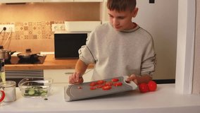 Teenage chef preparing fresh salad, precisely cutting ripe tomatoes and adding sliced cucumbers into clear glass bowl within modern kitchen setting - Powered by Shutterstock - Get 15% off with code: PIKWIZARD15