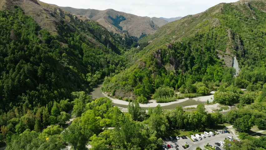 Aerial Scenic Shot Of River Amidst Green Mountains, Drone Flying Forward On Sunny Day - Arrowtown, New Zealand
