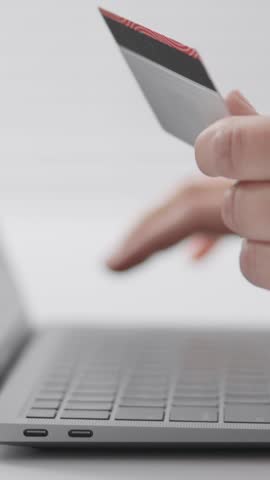 A person is holding a credit card while actively using a laptop to engage in online shopping, which has become a popular and convenient way to make purchases in todays digital marketplace