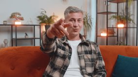 Hey you. Happy satisfied man with gray hair smiling excitedly and pointing to camera, choosing lucky winner, indicating to awesome you, inviting, approve at home. Young guy sitting in room on couch - Powered by Shutterstock - Get 15% off with code: PIKWIZARD15