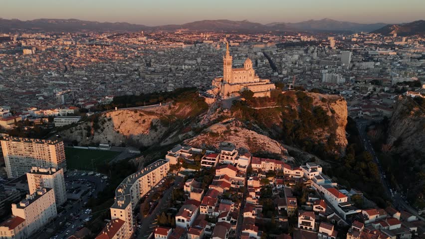 Aerial sunset view of Marseille city in France , drone approaching the Notre-Dame de la Garde Catholic basilica during golden hours