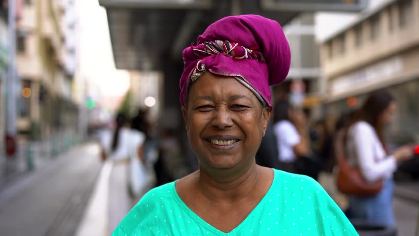 Happy african senior woman smiling on camera while wearing traditional clothes and turban in the city - Religion, culture and urban lifestyle concept