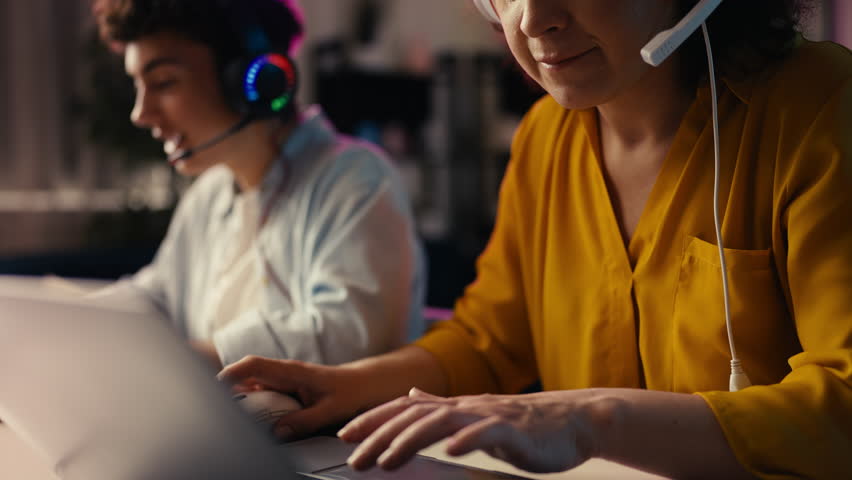 Excited mother and her teen son playing a video game on laptops as a team