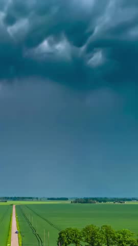 Vertical - Storm Clouds Above Green Farm Fields On Dramatic Weather. aerial hyperlapse