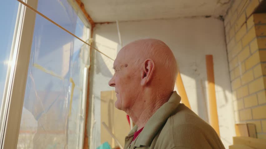 Elderly craftsman reflecting on years of artistry in a sunlit workshop filled with colorful materials