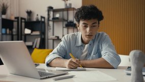 Teenager studying at home, writing in a notebook and using a laptop for research - Powered by Shutterstock - Get 15% off with code: PIKWIZARD15