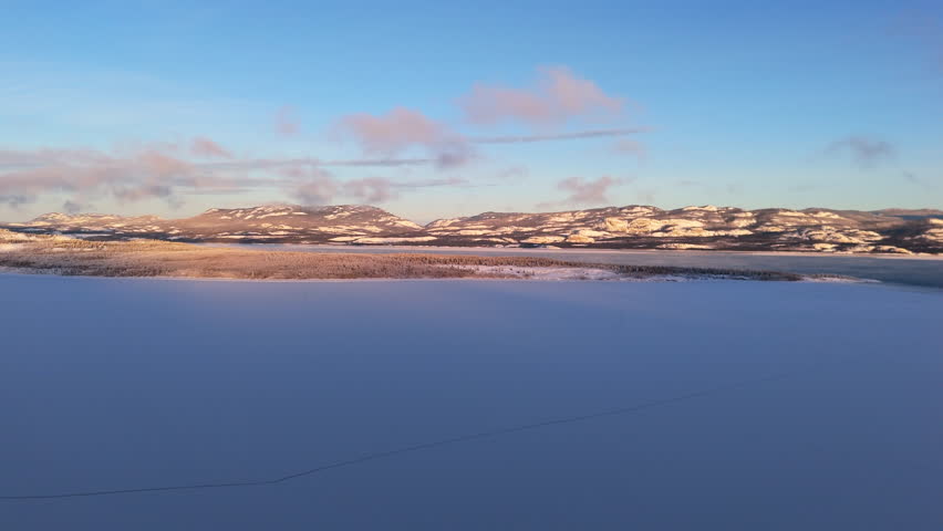 Frozen Lake Laberge With Snow-covered Mountains In The Background In Yukon, Canada. - aerial shot