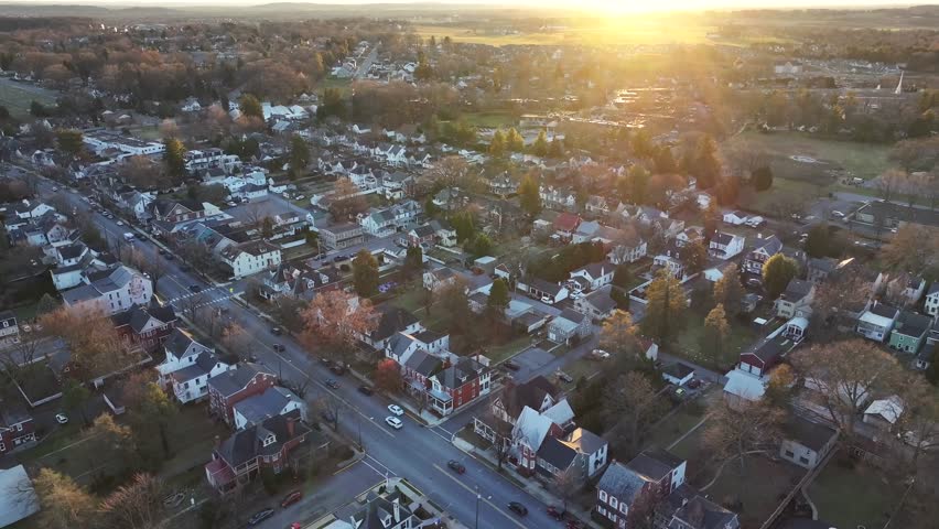 Small town in USA. Victorian and colonial homes line street as sunset. Colorful winter establishing shot. Aerial wide shot. Traffic on main street.