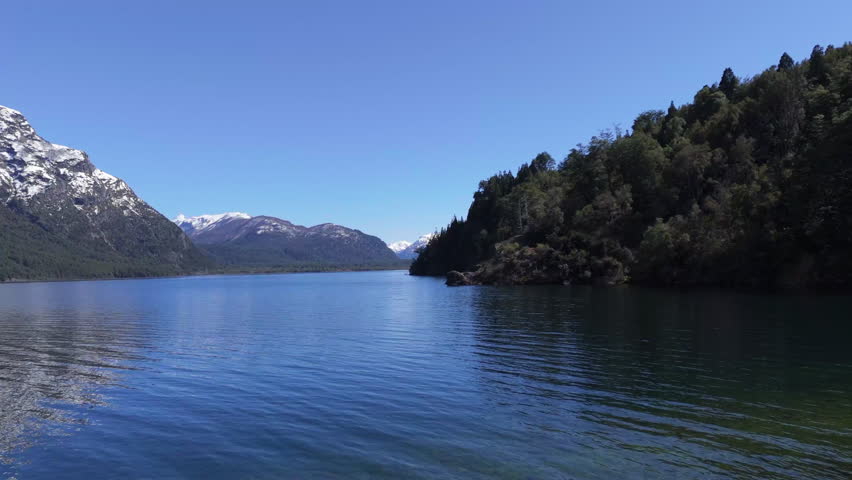 Deep blue waters reflecting snowy mountains and lush vegetation in Lago Futalaufquen, a stunning destination nestled in Parque Nacional Los Alerces in the heart of Argentinian Patagonia, static shot