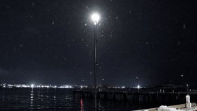 A serene nighttime view of the Halifax waterfront, featuring a beautifully illuminated light on the boardwalk surrounded by gently falling snow. - Powered by Shutterstock - Get 15% off with code: PIKWIZARD15