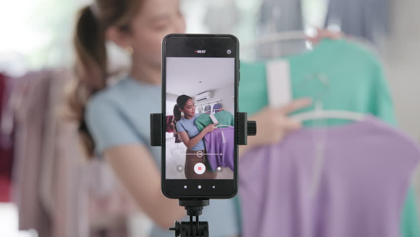 Gen Z vlogger SME owner go green net zero thrift store sale live stream talk on mobile social media online second hand sell. Asia people young woman record home video camera app eco shop side hustle.