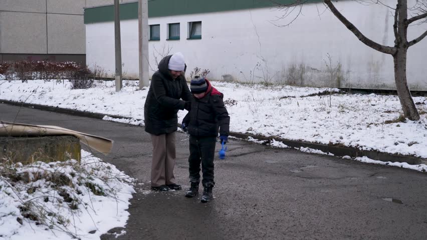 A mother and her son put their snowy clothes in order.