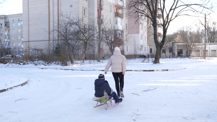 Mother and son are sledding. Winter entertainment.