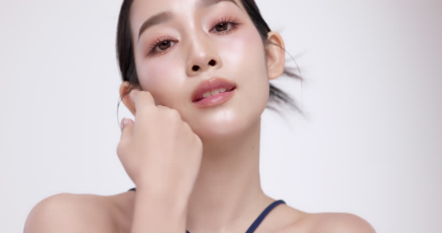 Slow motion of beautiful young Asian girl with glowing skin and k-beauty make up style on isolated white background for commercial beauty advertising.