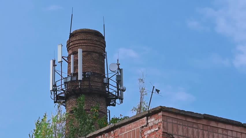 Cellular antennas and Internet on the brick pipe. 5G antennas mounted on a brick chimney against a blue sky