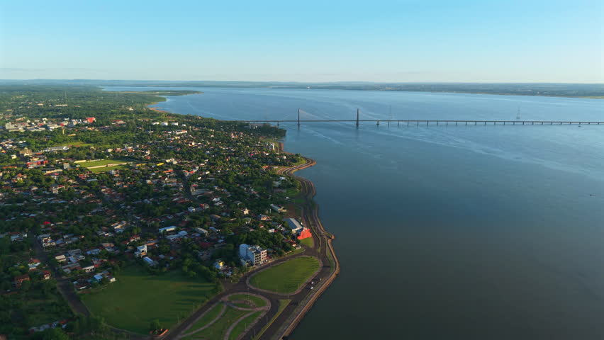 Bridge crossing Paraguay and Argentina Paraná river border, Aerial view of Encarnación city, waterfront landscape