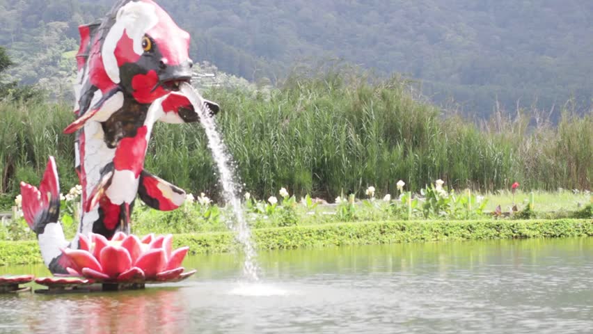 Fish statues in a fish pond with mountains in the background