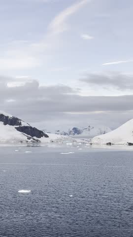Sunset of the Polar seascape of Antarctica with icebergs floating in the ocean and glacier in the background. Stunning Antarctic landscape under moody and cloudy skies.