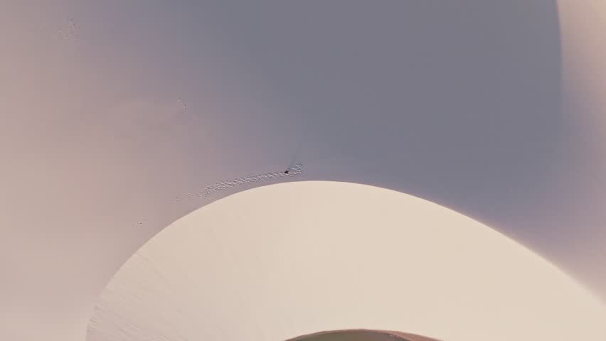 Aerial shot drone view boy or man walking in the white sand dunes of the Lencois Maranhenses in Maranhao, Brazil. UNESCO World Heritage Site. Establishing Shot.