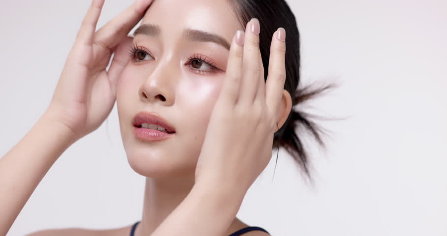 Slow motion of beautiful young Asian girl with glowing skin and k-beauty make up style on isolated white background for commercial beauty advertising.
