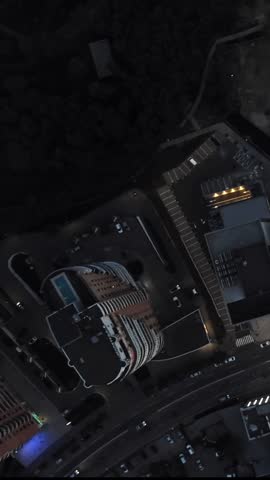 Aerial moody look down on evening city rooftop with cars driving busy streets