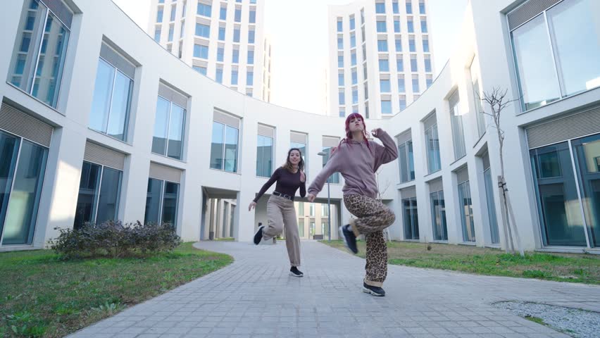 Young women dancing outside modern building