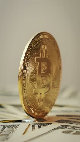 Golden bitcoin rotating on dollar bill background. Bitcoins virtual currency. Cryptocurrency. BTC. Bitcoin mining. Macro shot of rotating bitcoin. Stock exchange market. Vertical video
