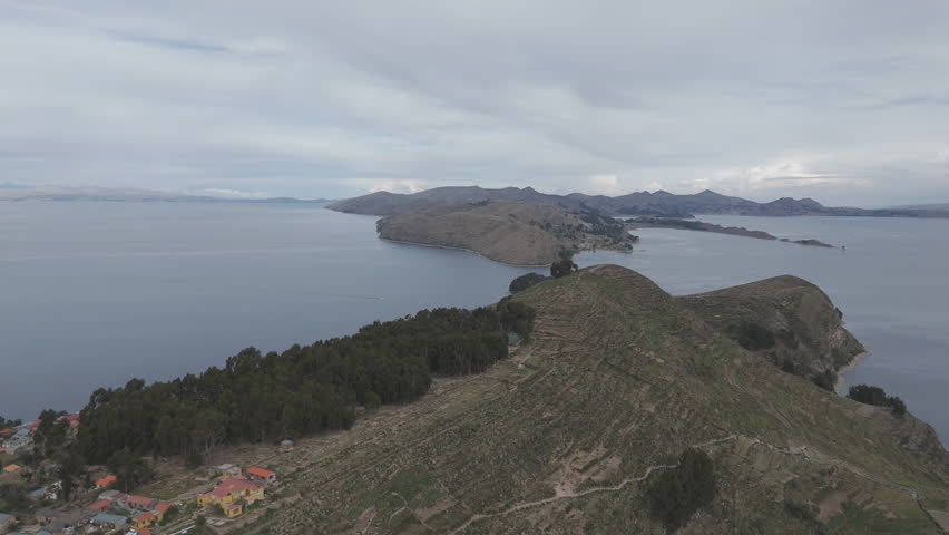 Drone shot above Isla Del Sol near Copacabana Bolivia Titicaca lake on a cloudy day with view on the sea and the islands LOG