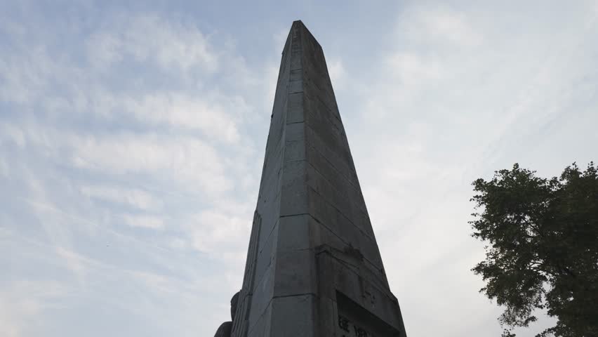 Tall stone monument honoring the 14th Line Regiment in Liege, Belgium, under cloudy skies