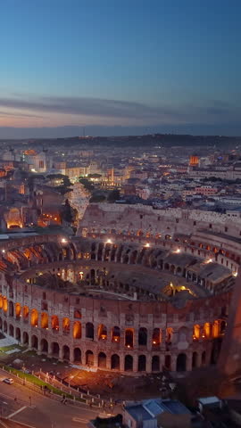 Vertical Aerial View of Beautiful sunset over the illuminated Colosseum in Roma with a vibrant skyline and city lights. Italy