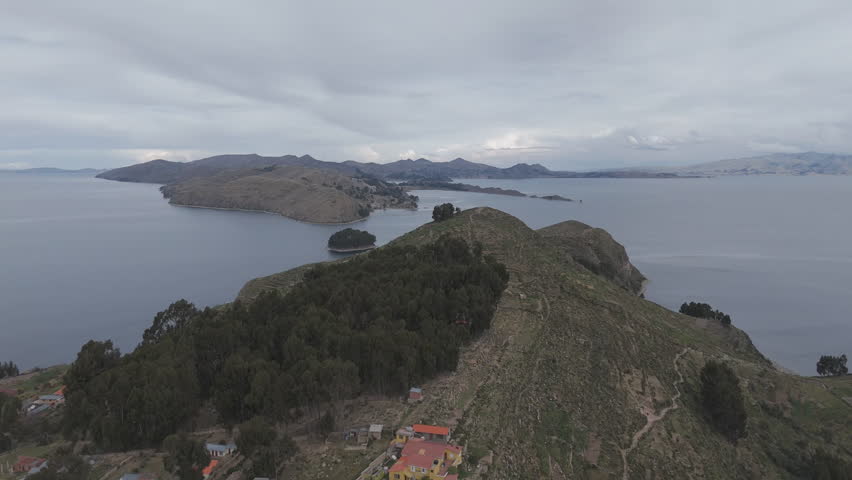 Drone shot above Isla Del Sol near Copacabana Bolivia Titicaca lake on a cloudy day with view on the sea and the islands LOG