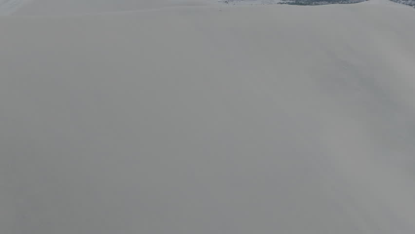 Drone shot revealing the city of Huacachina in Peru behind the dunes on a cloudy day LOG
